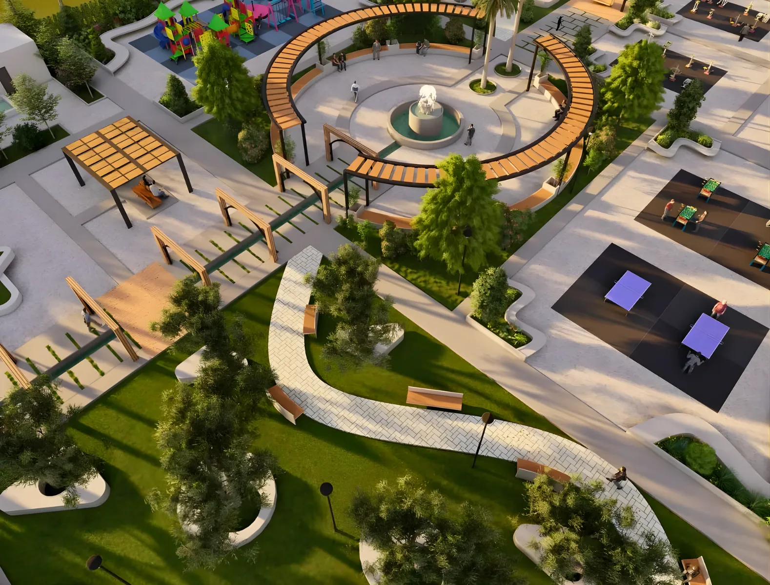 Aerial view of a modern park with winding paths, green lawns, trees, benches, a circular fountain plaza, covered seating areas, a playground, and sports courts. People are scattered throughout the park.